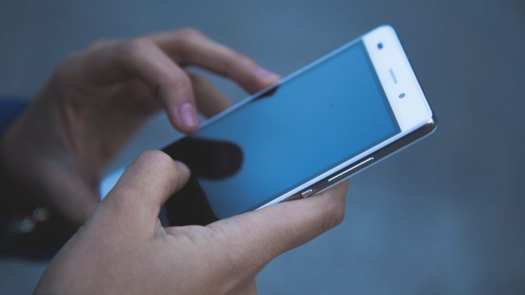 手にスマートフォンを持って操作している様子